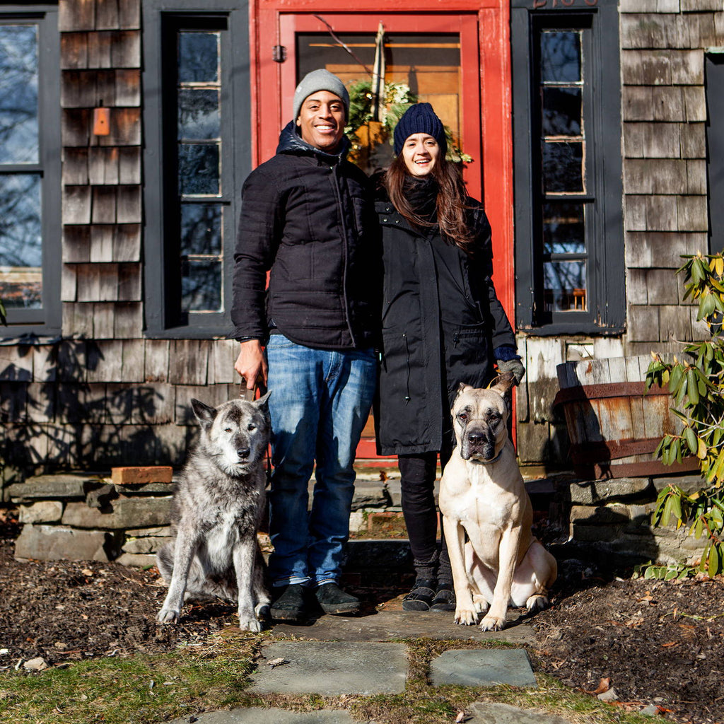 A couple and their two dogs stand in front of a dog-friendly inn